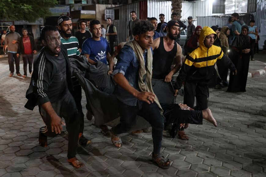 Palestinians carry a victim of the Israeli strike on a mosque-turned-shelter in Deir al-Balah