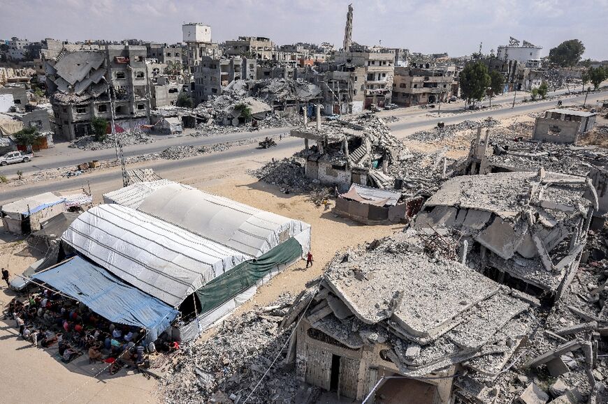 Muslim worshippers perform the weekly Friday prayers in a tent enclosure by destroyed buildings in Gaza's Khan Yunis