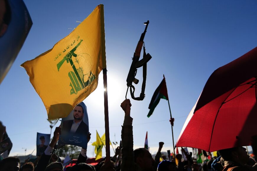 Yemenis raise a Lebanese Hezbollah flag and a rifle during a rally in the Huthi-controlled capital Sanaa