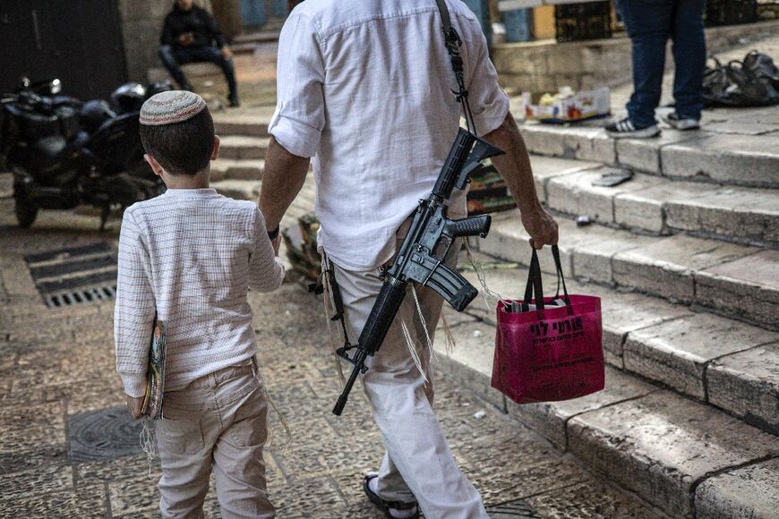 An armed ultra-Orthodox Jewish man holds a child by the hand as he walks in the Old City in Jerusalem at the start of the Jewish holiday of Yom Kippur