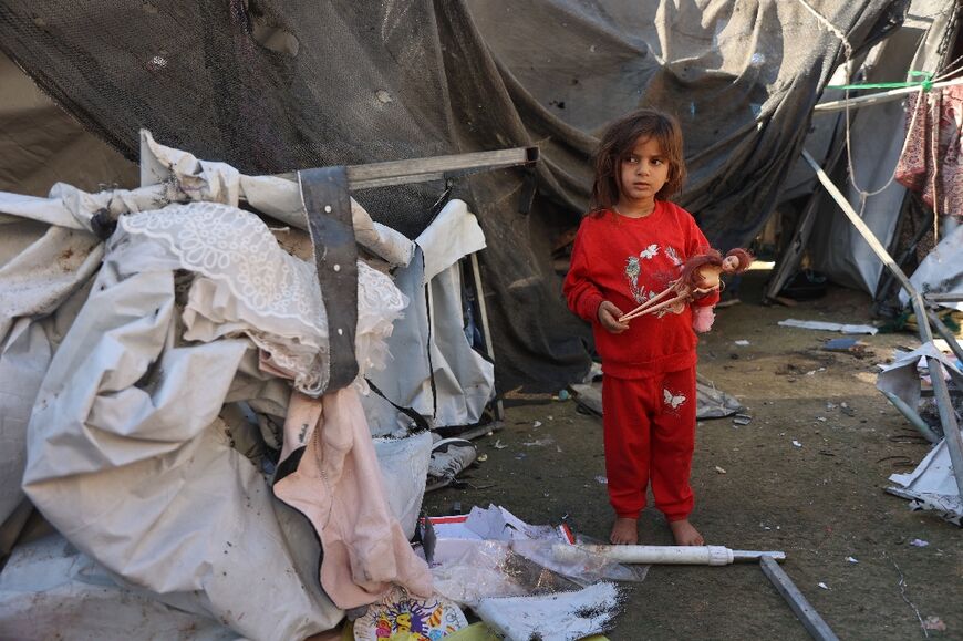 A Palestinian girl stands next to a tent in a displaced persons' camp in Gaza City damaged in an Israeli bombardment.