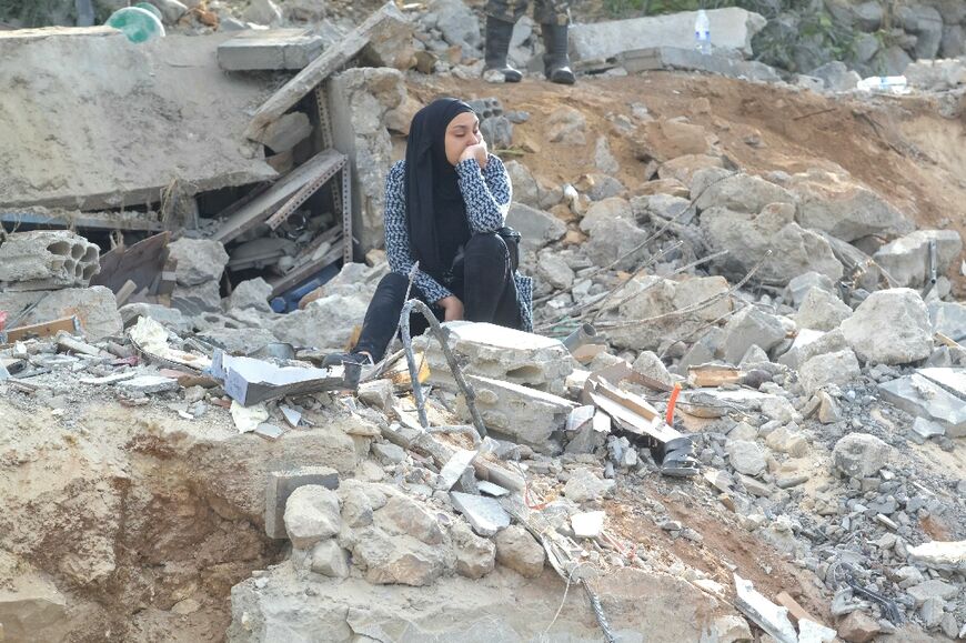 A woman reacts while sitting on the rubble at the site of an Israeli strike in Ain Yaacoub, Akkar region, on November 12, 2024, amid the ongoing war between Israel and Hezbollah.