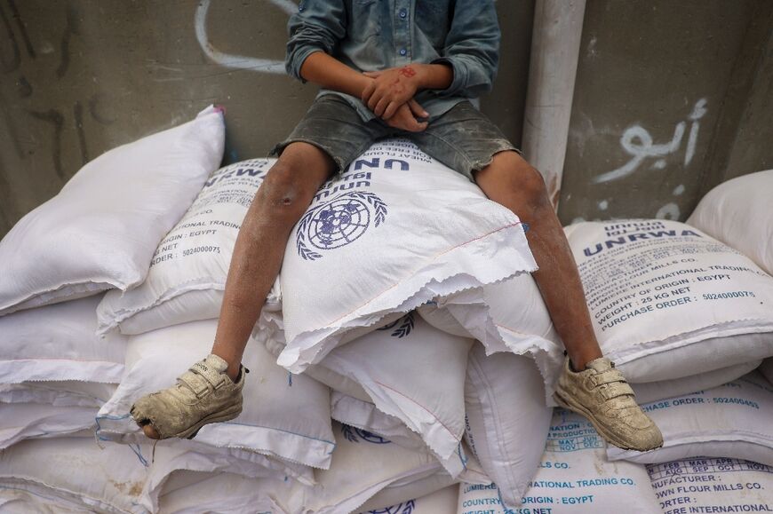 A Palestinian child sits on flour sacks at an UNRWA aid distribution centre in Deir el-Balah in central Gaza