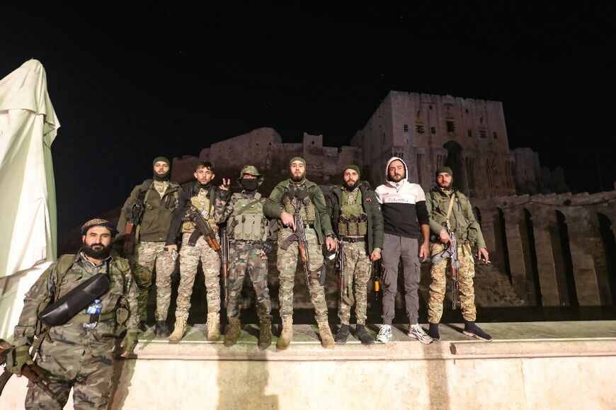 Anti-government fighters, who have made a lightning offensive, pose for a picture in front of Aleppo's landmark citadel