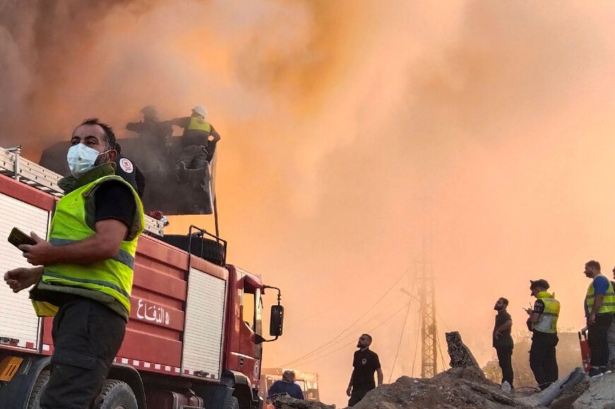 In the southern Lebanese city of Tyre, firefighters and rescuers gather in front of a building set ablaze by an Israeli air strike