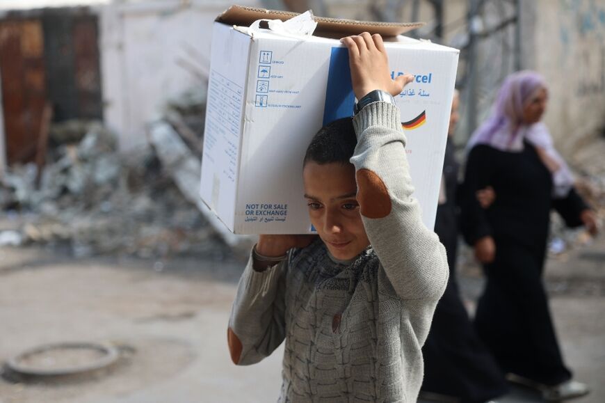 A boy carried a box of humanitarian aid back to his home in central Gaza's Al-Bureij refugee camp