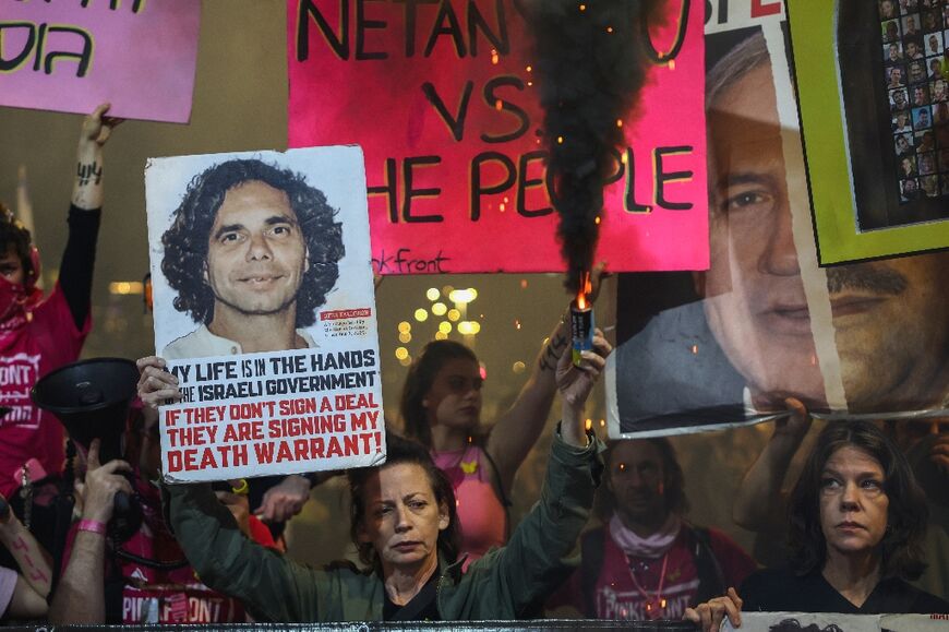 A demonstrator in Tel Aviv holds a flare while carrying a portrait of Ofer Kalderon, an Israeli held hostage by Palestinian militants in Gaza, during a protest demanding action for their release 