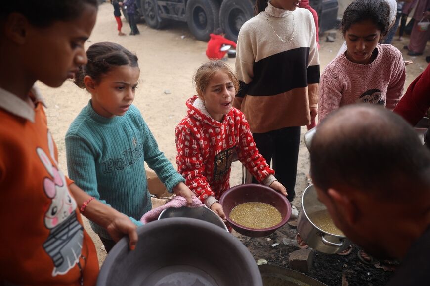 Palestinian children receive a hot meal at the Bureij refugee camp in central Gaza on November 16, 2024