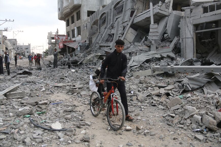 A young Palestinian pushes his bicycle amid the rubble following Israeli strikes in Nuseirat refugee camp in central Gaza