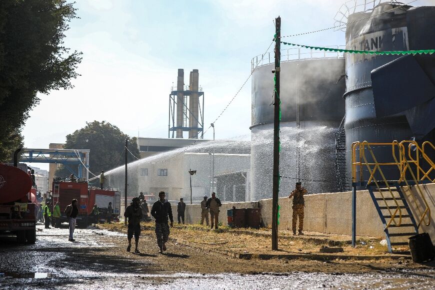 Yemeni firefighters douse oil tanks with water at a power station hit by an Israeli air strike in Sanaa