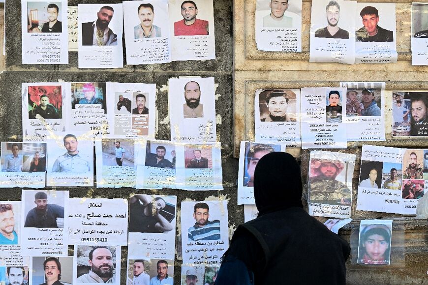 A Syrian woman looks at notes for missing people posted at Damascus's Marjeh Square