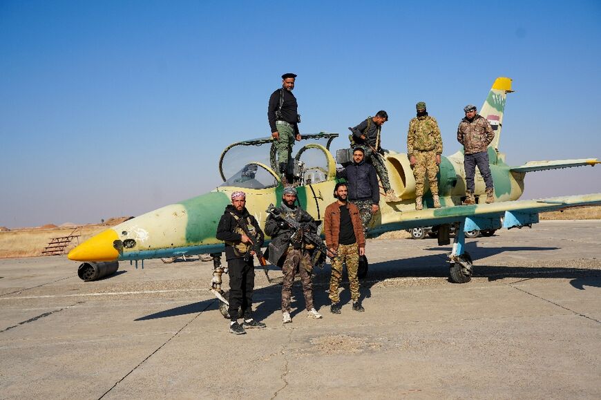 Anti-government fighters pose for a picture on a Syrian regime military aircraft at an airfield in Aleppo province