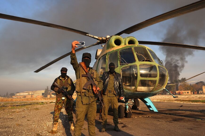 Rebel fighters celebrate alongside a captured army helicopter at the Nayrab air base in Syria's second city Aleppo.