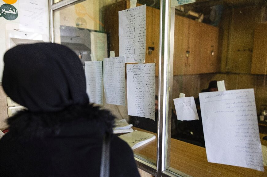 A Syrian woman looks for the name of her missing brother on lists of dead prisoners from the notorious Saydnaya prison, displayed on a window at a Damascus hospital