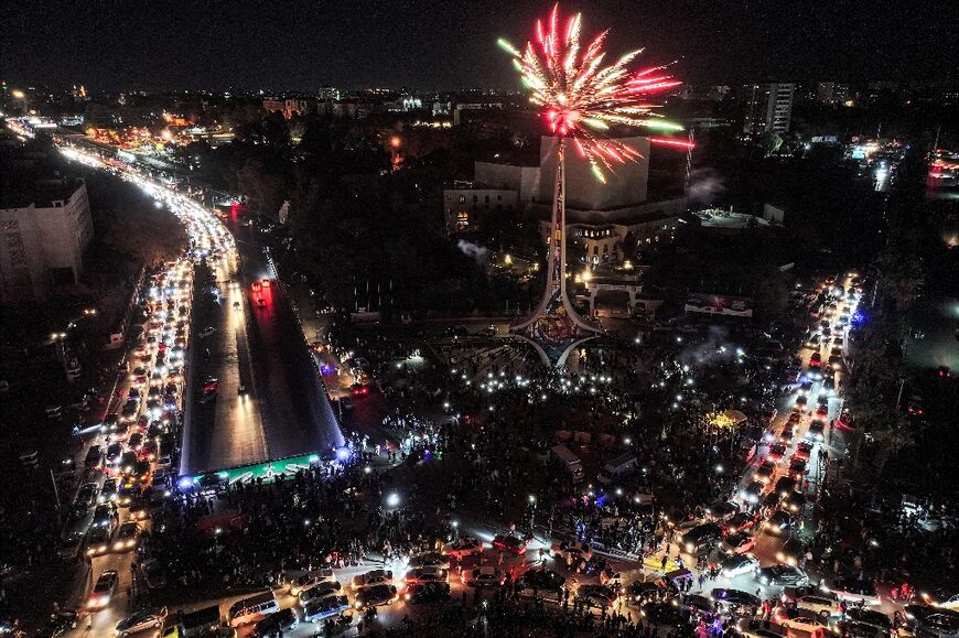 Fireworks erupt above people celebrating the ouster of Syrian president Bashar al-Assad at Umayyad Square in central Damascus