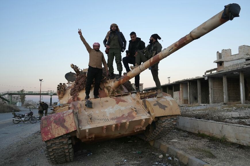 Anti-government fighters pose for a picture on a tank on the road leading to Maaret al-Numan in Syria's northwestern Idlib province