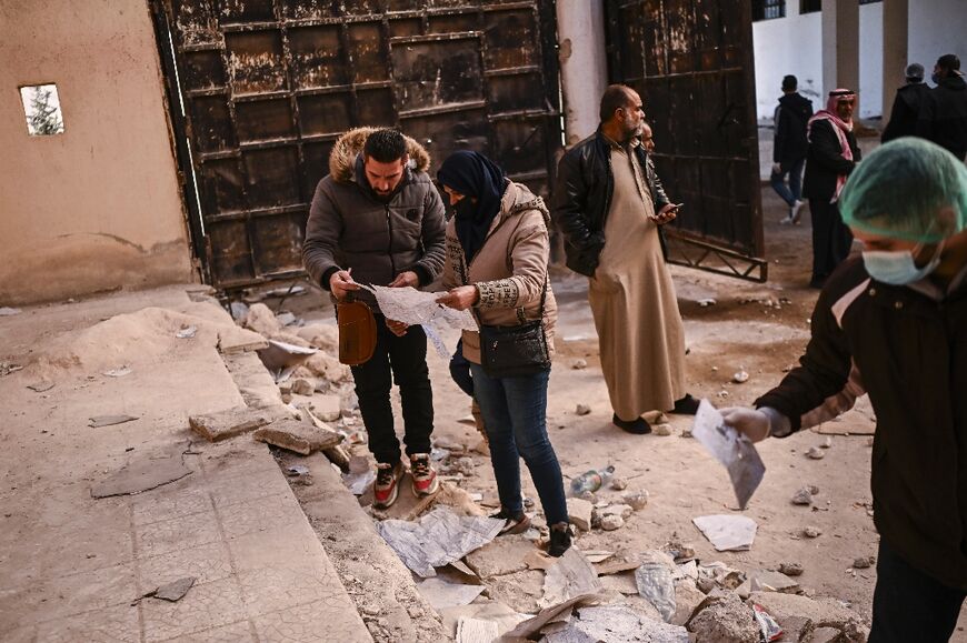 People searching for missing relatives look at damaged documents at the Saydnaya prison, north of the Syrian capital Damascus