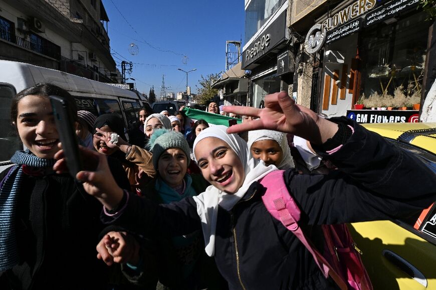 Schoolchildren wave the independence-era flag in the Dweilaa neighbourhood of Damascus on December 15