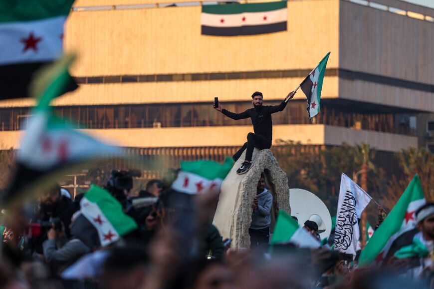 People wave independence-era Syrian flags during celebrations for the ousting of president Bashar al-Assad at Umayyad Square in the capital Damascus 