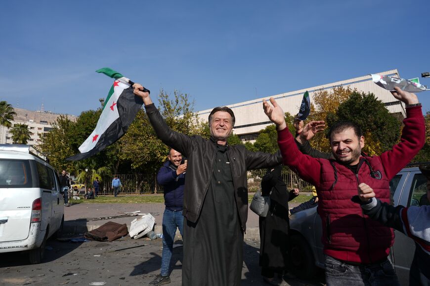 Men in Damascus celebrate the changing of the guard in Syria, one waving the new flag, on December 11, 2024. Photo credit: Morhaf Kiwan.