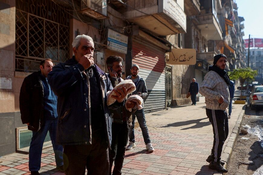 Syrian men hold packs of bread they got from a local bakery in central Aleppo