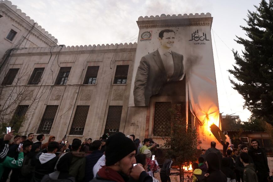 Hama residents set fire to a giant poster of Syrian President Bashar al-Assad on the facade of city hall after his forces abandoned the city