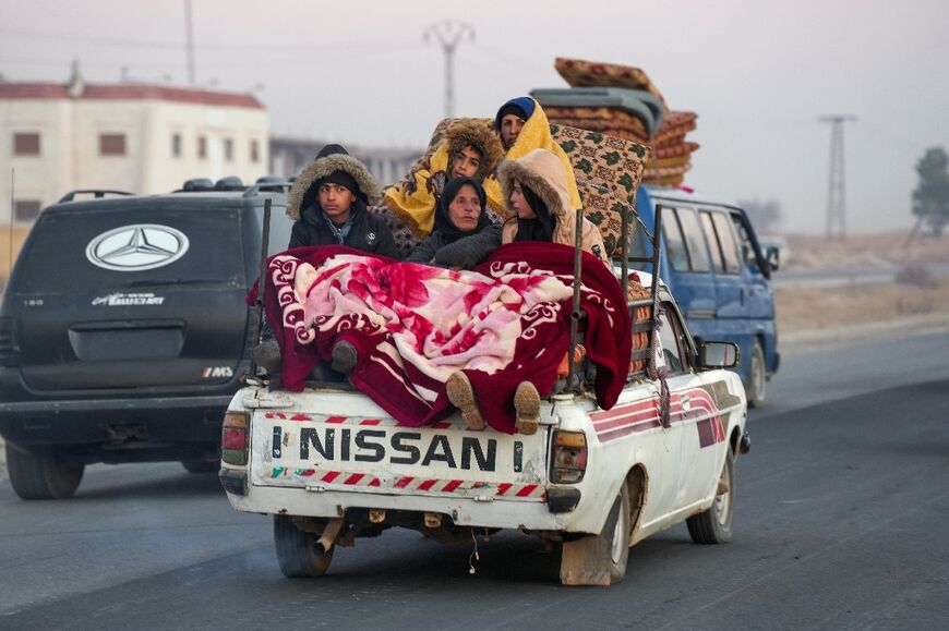 Displaced Syrian Kurds ride in the back of a vehicle loaded with belongings on the Aleppo-Raqqa highway