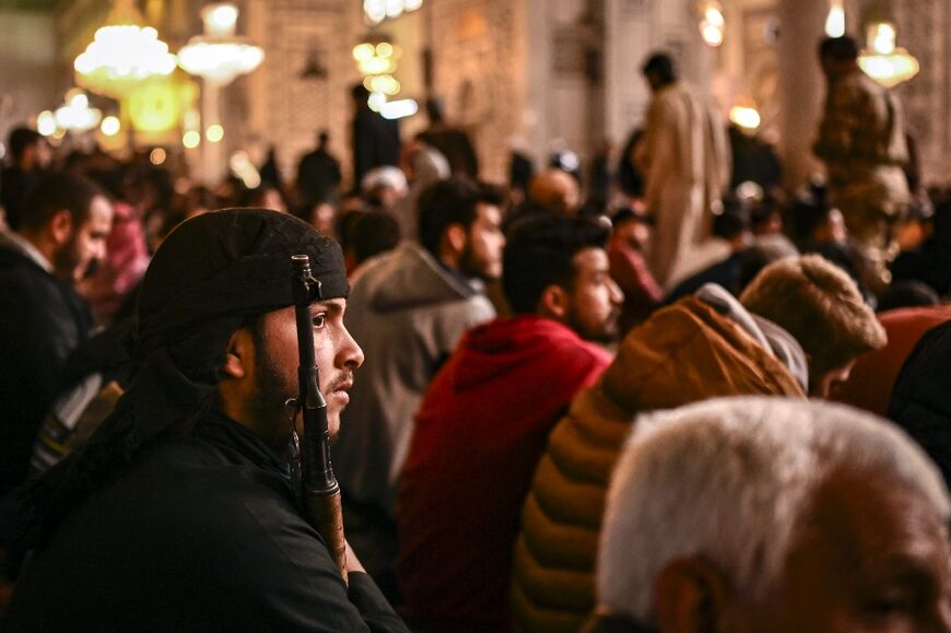 An armed rebel looks on as worshippers attend Friday prayers at the Umayyad Mosque