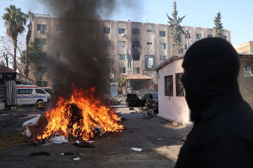 A man watches on as Syria's new authorities burn drugs reportedly seized from a security branch in Damascus