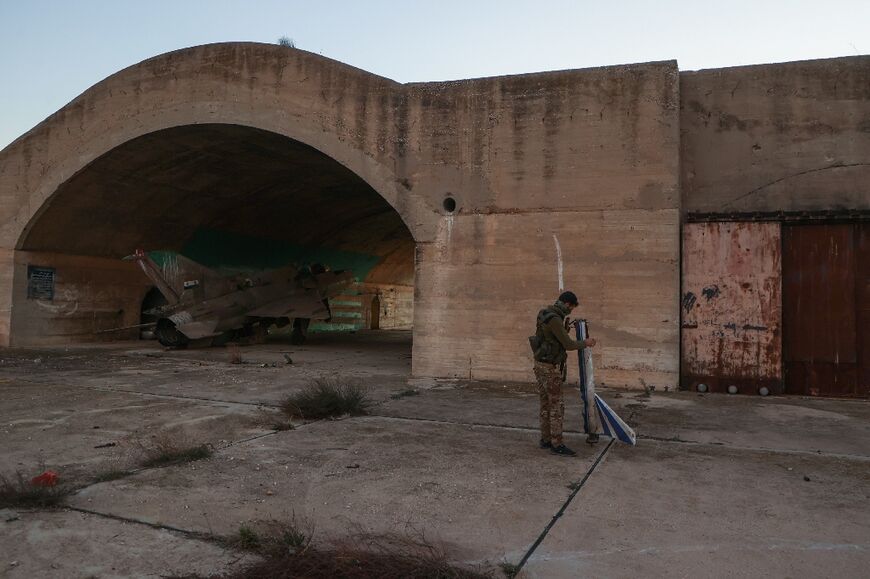 A rebel fighter inspects abandoned military equipment at al-Dabaa military airport in Syria's Homs province 