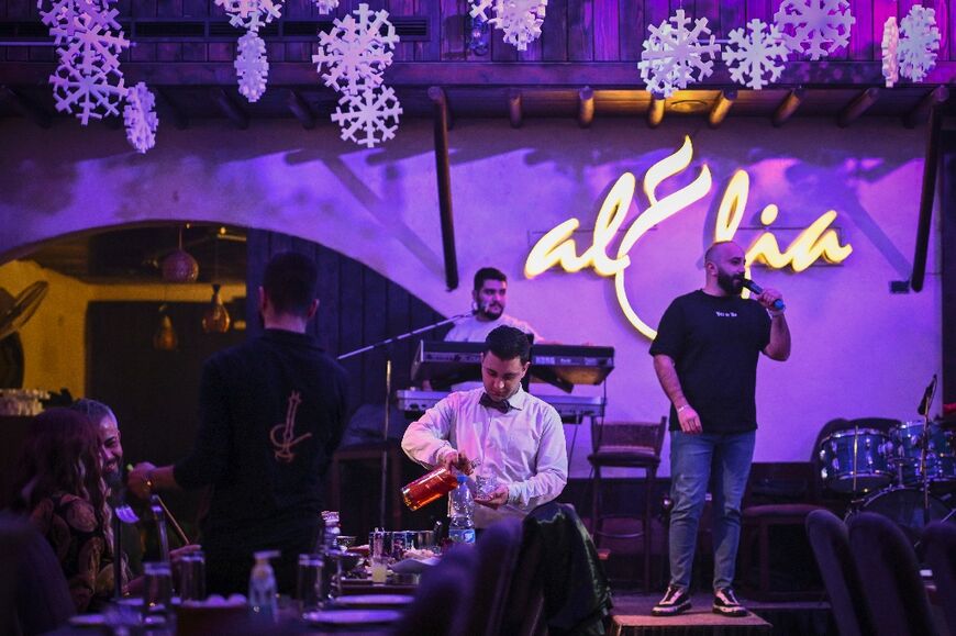 A waiter serves whisky to diners at a Damascus restaurant.