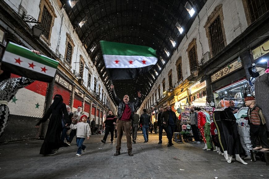 A man holds up a Syrian opposition flag along an alley of the Hamidiyah market in Old Damascus