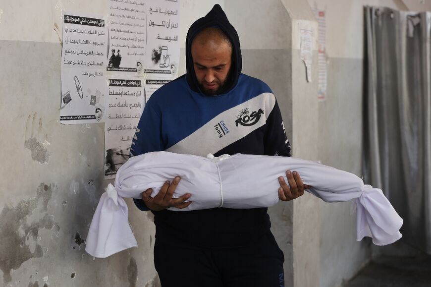 A Palestinian man carries the body of a child killed in overnight Israeli air strikes on Gaza City 