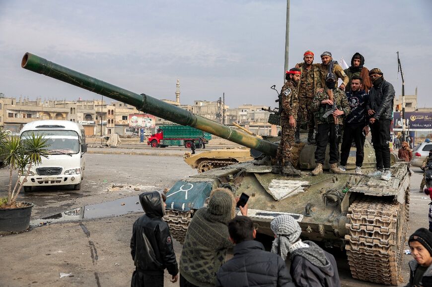 A man in Homs poses for pictures with fighters and security forces loyal to the new Syrian authorities after Assad was toppled